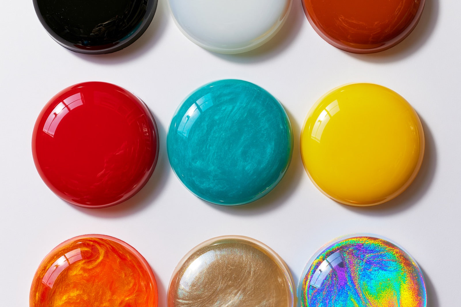 Discos de resina epóxi curada em nove cores, mostrando acabamento sólido, perolado e holográfico
